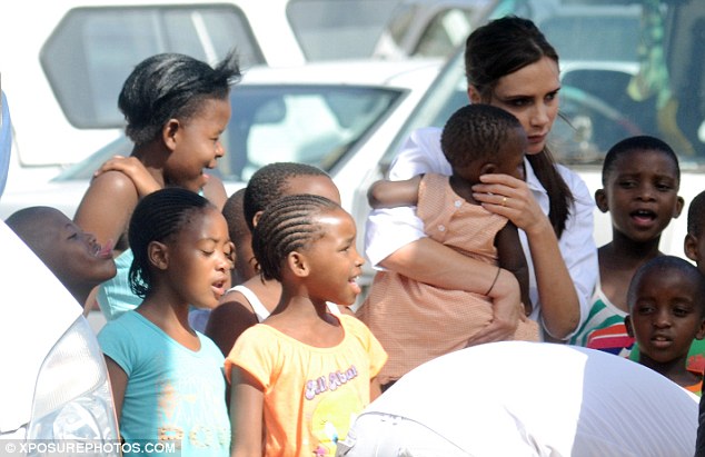 Exploitation: Victoria Beckham surrounded by children in Cape Town, while celebrity photographer Annie Leibowitz clicks away.